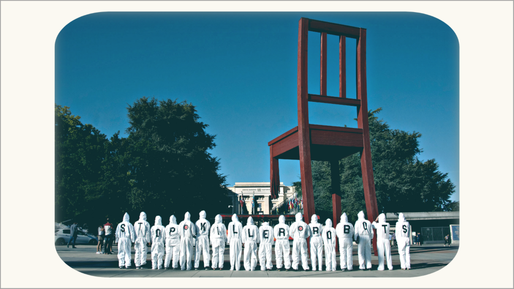 Acción de campaña frente a las Naciones Unidas en Ginebra con activistas en trajes de caldera blancos leyendo 'Stop Killer Robots'.