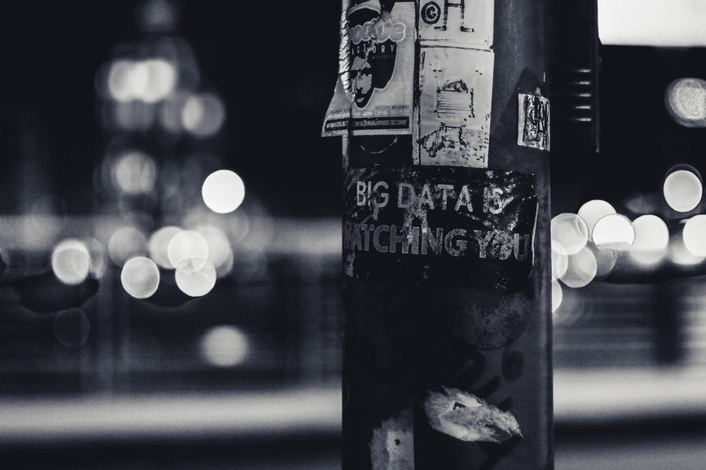 An image of a pole with the words “bit data is watching you” written on it.