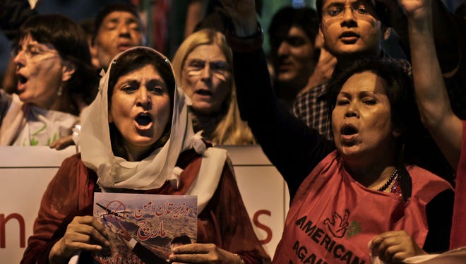 Pakistani and American citizens hold banners and chant slogans against drone attacks in Pakistani tribal belt