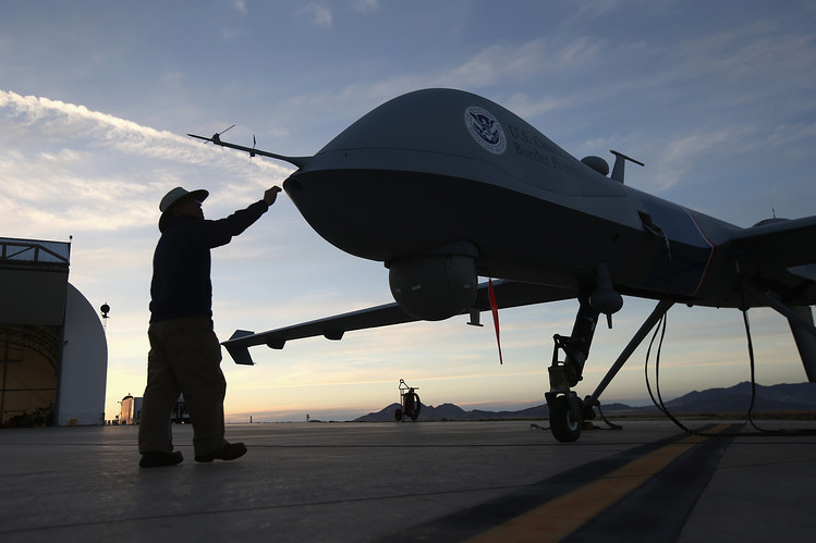 silueta de drone contra el telón de fondo del atardecer con una persona que se acerca para tocarlo